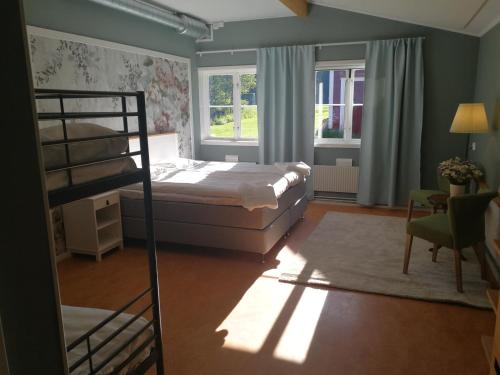 a bedroom with a bunk bed and two windows at Sjugare Gård Bed & Breakfast in Leksand