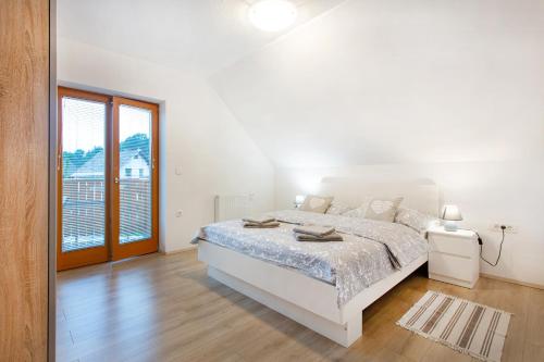 a white bedroom with a bed and a large window at Apartments Roberta in Bled