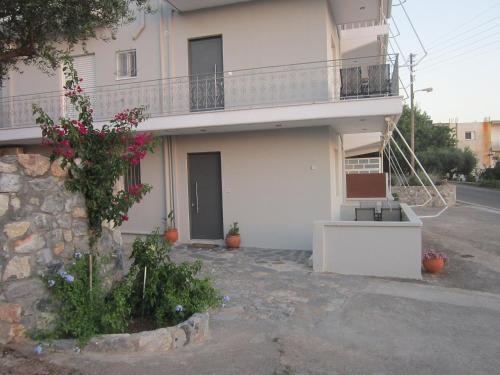 a large white house with a balcony and flowers at Blue Yard Apartments in Kalamata
