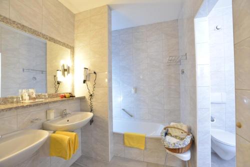 y baño blanco con bañera, lavamanos y bañera. en Hotel Residenz Hochland en Seefeld in Tirol