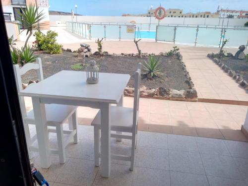 a white table and chairs with a view of a pool at Apartamento SUN Complex Amaya Fuerteventura in Costa de Antigua