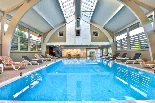 an indoor swimming pool with chairs and a large ceiling at Le Pré de la Cure in Yvoire