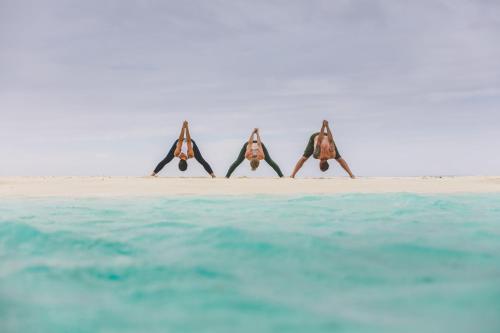 a group of four people doing yoga on the beach at Tamanu Beach in Arutanga