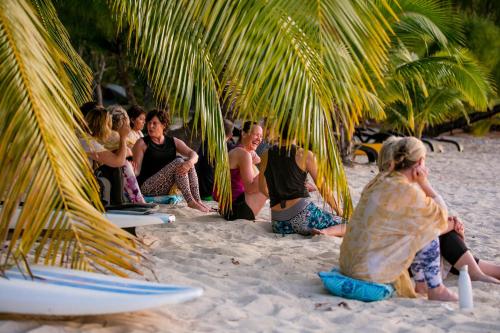 a group of people sitting under palm trees on a beach at Tamanu Beach in Arutanga