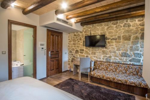 ein Schlafzimmer mit einem Sofa und einer Steinmauer in der Unterkunft Hotel Arhontiko Vourloka in Pramanta