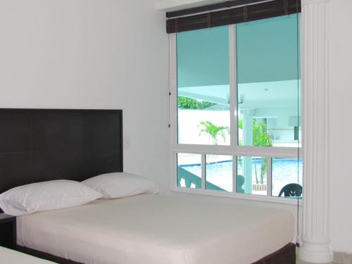 a bedroom with a bed and a large window at Hotel Iraqúa in Acacías