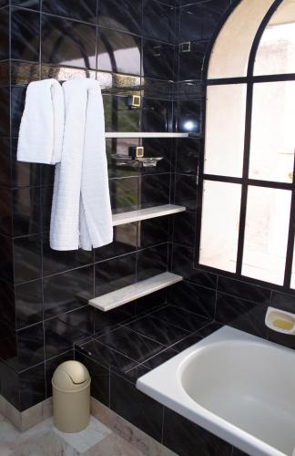a black tiled bathroom with a bath tub and towels at Lo de Viviana in San Salvador de Jujuy