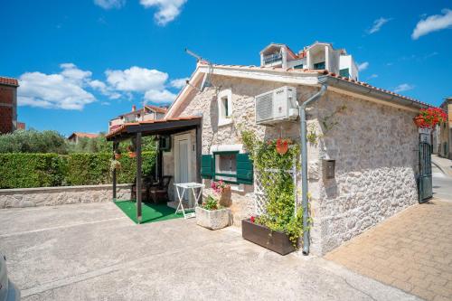 una pequeña casa de piedra con flores en la fachada en Apartments Janjac, en Vodice