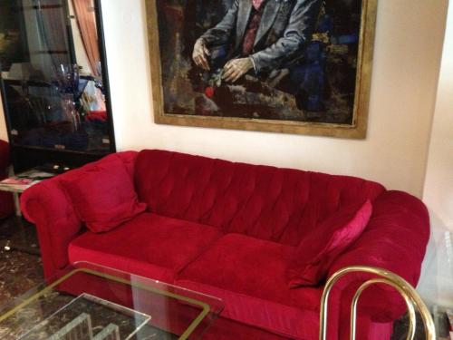 a red couch in a living room with a painting at Hotel Montree in Munich