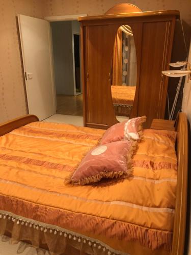 a bed with an orange comforter and a mirror at Apartments Kohtla-Jarve in Kohtla-Järve