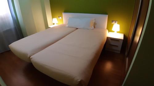 1 cama blanca grande con 2 luces al lado en Apartaments Júlia, en La Pobla de Segur