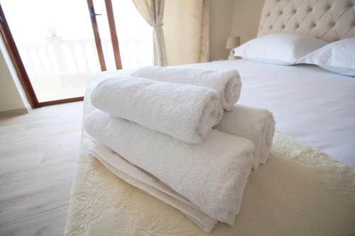 a pile of white towels sitting on top of a bed at Apartments Romario in Sarandë