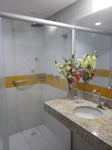 a bathroom with a sink and flowers on a counter at Pipa's Ocean - Flat Vista Mar in Pipa