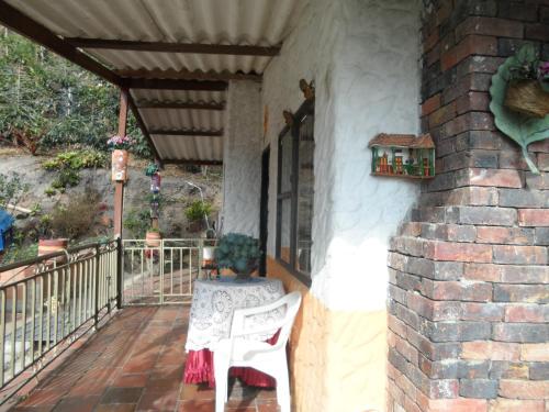 a porch with a white chair and a brick wall at Casa finca El Girasol in Guayabal de Síquima