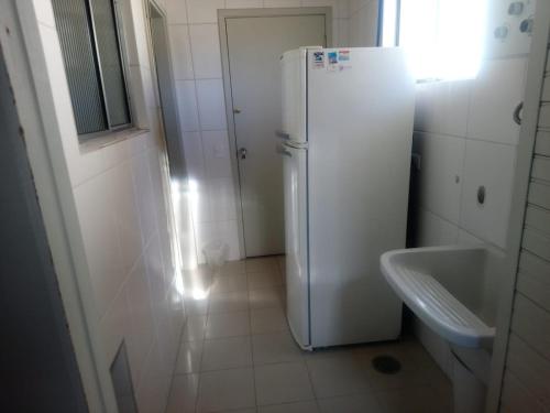 a white refrigerator in a bathroom with a sink at Apartamento no Centro de Campos do Jordao in Campos do Jordão