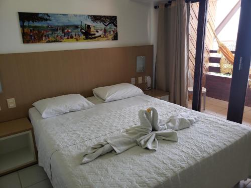 a bedroom with a bed with a bow on it at Pipa's Ocean - Flat Vista Mar in Pipa