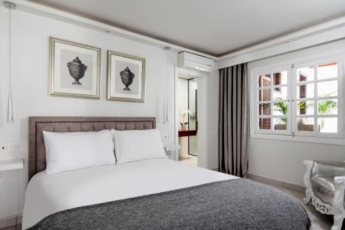 une chambre avec un lit blanc et une chaise dans l'établissement Drago by AGM Resorts, à Puerto del Carmen