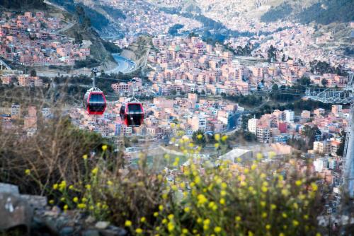 two red cable cars flying over a city at Hotel Gloria La Paz in La Paz