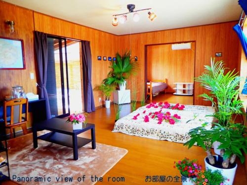 ein Schlafzimmer mit einem Bett mit rosa Blumen drauf in der Unterkunft Yakushima Cottage Kukai in Yakushima