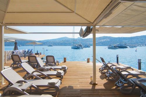 a bunch of chairs sitting on a dock near the water at Marisol Boutique Hotel in Gundogan