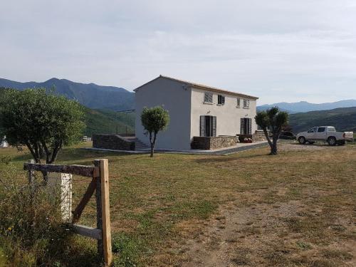 ein weißes Haus mit einem Auto auf einem Feld in der Unterkunft Entre mer et montagne, en plein maquis in Vallecalle