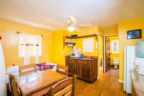 a dining room with yellow walls and a wooden table at Bananarama Dive & Beach Resort in West Bay