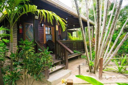 Bananarama Dive & Beach Resort في ويست باي: منزل صغير مع شرفة وبعض الأشجار