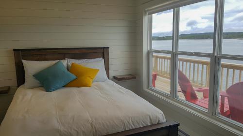 een bed met kleurrijke kussens in een kamer met een raam bij A Wave From it All in Port Saunders