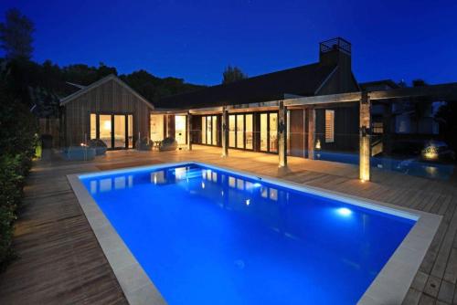 a swimming pool in front of a house at night at Blackpool Boathouse - Stay Waiheke in Oneroa