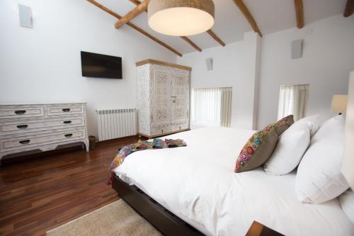 a bedroom with a white bed and a dresser at Tocuyeros Boutique Hotel in Cusco