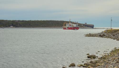 a red boat in a large body of water at A Wave From it All in Port Saunders