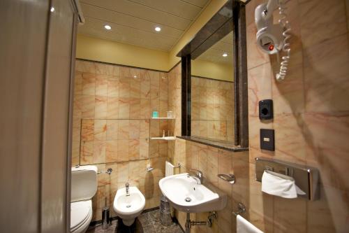 Baño con 2 lavabos y espejo en Mercure Reggio Emilia Centro Astoria, en Reggio Emilia