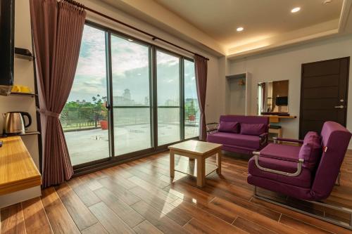 a living room with purple chairs and a large window at 123 Hall in Wujie