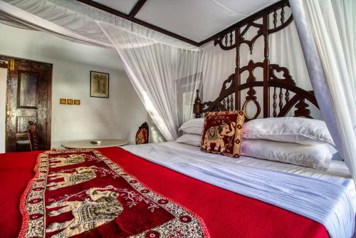 a bedroom with a large bed with a red blanket at Tembo House Hotel in Zanzibar City