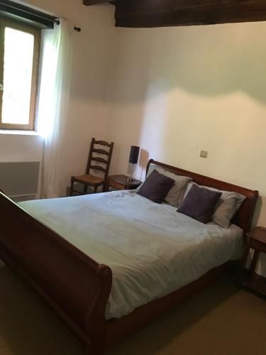a bedroom with a bed and a window and a chair at Domaine de la Ribiere in Pagéas
