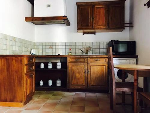 a kitchen with wooden cabinets and a table and a microwave at Domaine de la Ribiere in Pagéas