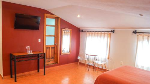 a bedroom with a bed and a table and chairs at Hotel Casa Margarita in San Cristóbal de Las Casas