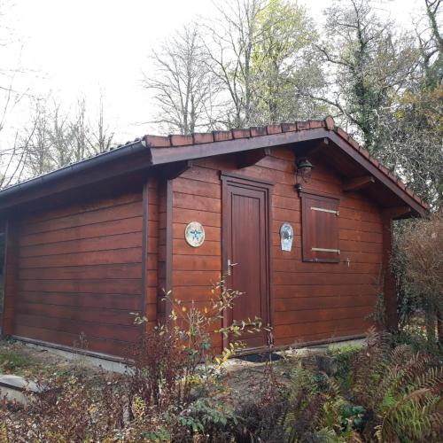 a small wooden cabin with a door in the woods at Domaine de la Ribiere in Pagéas