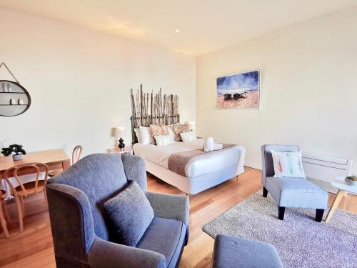 a living room with a bed and a couch and chairs at Phoenix Apartments in Lorne
