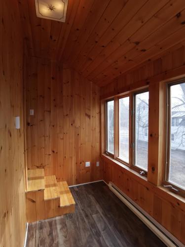 an empty room with wooden walls and windows at By The River B&B in Fredericton