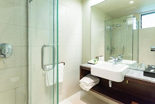 アロフィにあるシーニック マタバイ リゾート ニウエのバスルーム(洗面台、ガラス張りのシャワー付)