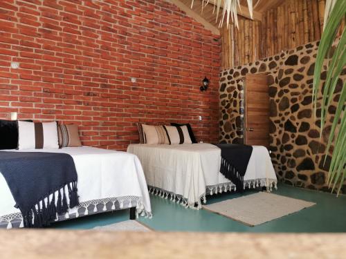 two beds in a room with a brick wall at Villa Armonia Hotel & Spa in Jocotepec