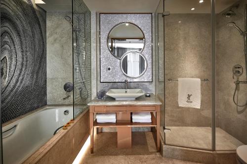 uma casa de banho com um lavatório, uma banheira e um espelho. em Dorsett Wanchai, Hong Kong em Hong Kong