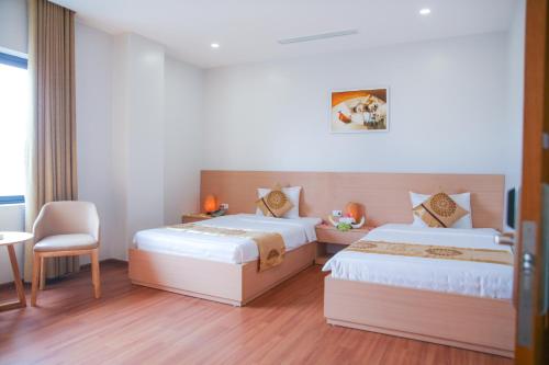 a hotel room with two beds and a chair at Long Anh Hotel in Thanh Hóa