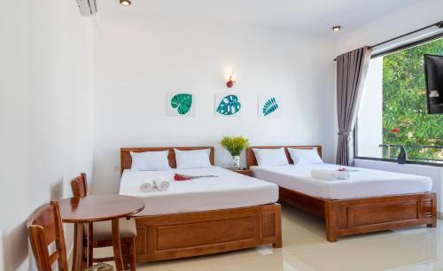 a bedroom with two beds and a table and a window at PaPa Villa Homestay in Hoi An