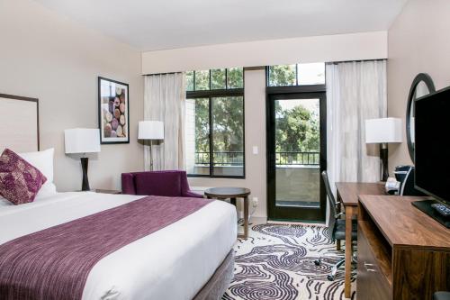 Habitación de hotel con cama, escritorio y ventanas en Hotel Siri Downtown - Paso Robles, en Paso Robles