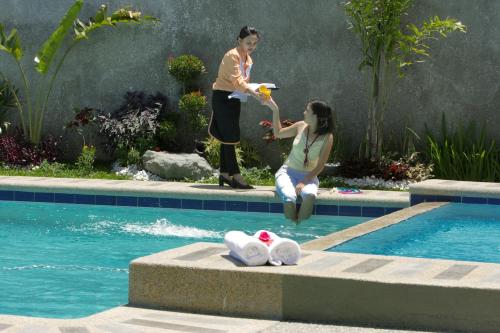 a woman is sitting next to a swimming pool at Hanan Hotel Tagaytay - Formerly Tagaytay Wingate Manor in Tagaytay
