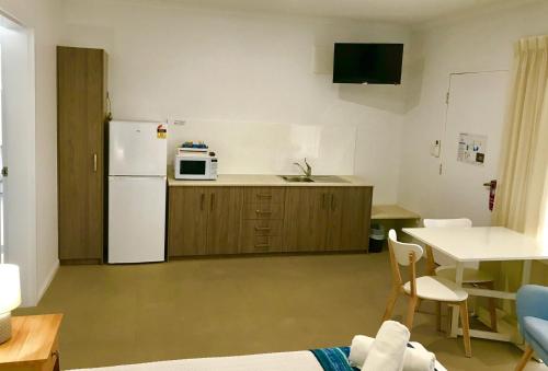 a small kitchen with a white refrigerator and a table at Cleveland Bay Air Motel in Cleveland