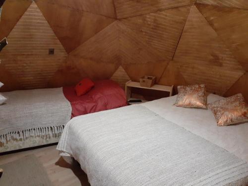 a bedroom with two beds in a room with a wooden wall at Domos Entre Bosques in Malalcahuello