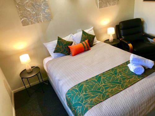 a bedroom with a bed with colorful pillows and a chair at Cleveland Bay Air Motel in Cleveland